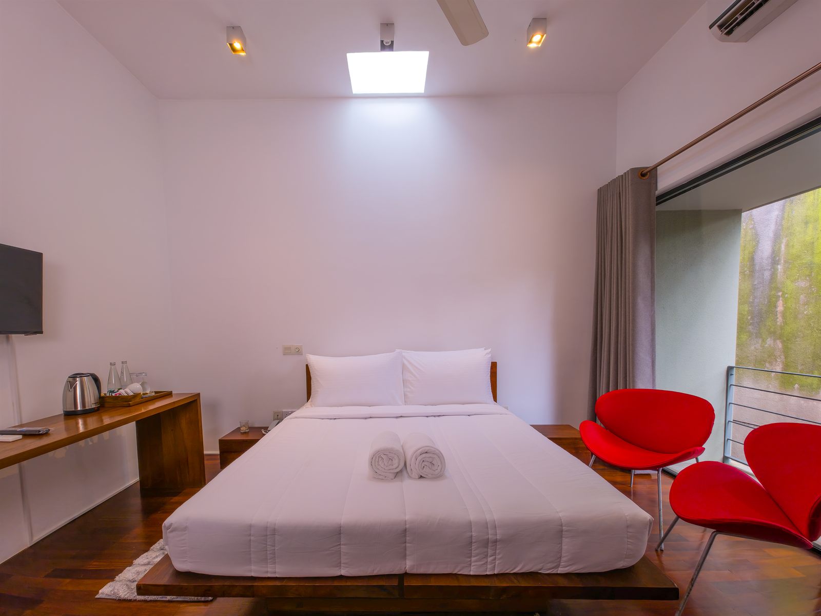 Deluxe Room bed with white linen and red chairs