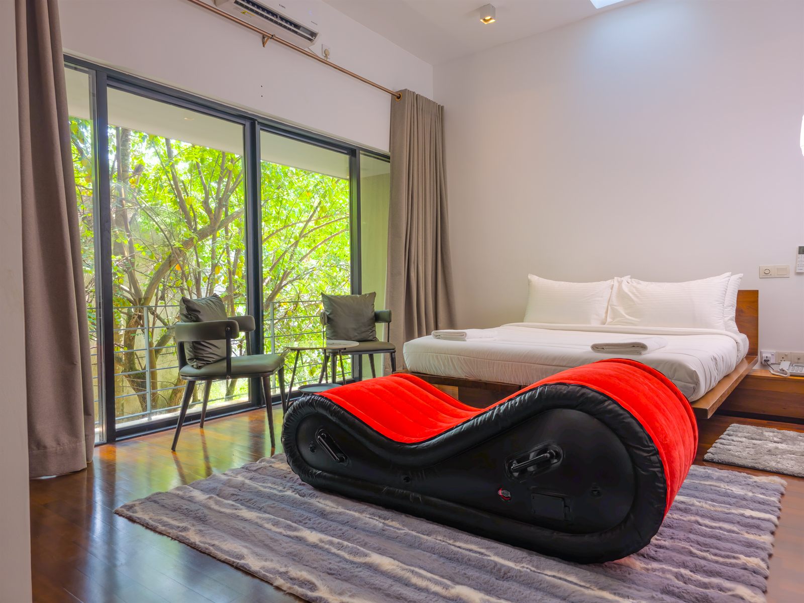 Superior Room bed with red lounge chair and garden-facing window